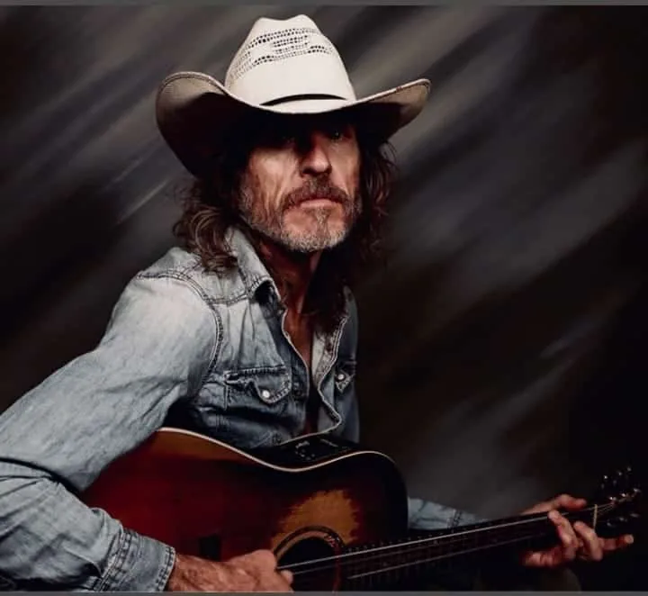 Mick Daley playing acoustic guitar in a cowboy hat